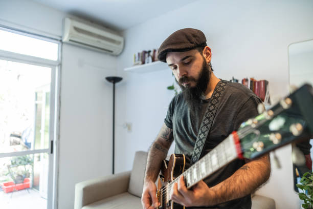 istock Mid adult man playing guitar at home 1742628862