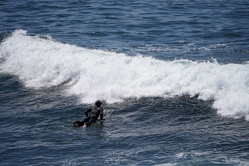 A young adult male on a surfboard in the ocean on a sunny day