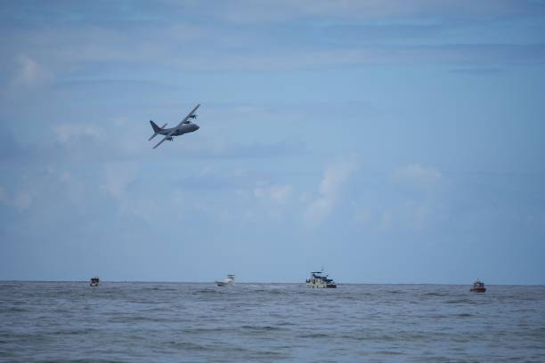 A small airplane soaring over a white boat sailing in the sparkling blue ocean