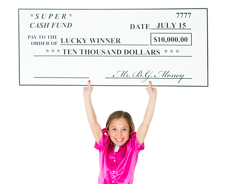 A young girl holding a jumbo sized prize check.  Isolated on a white background.