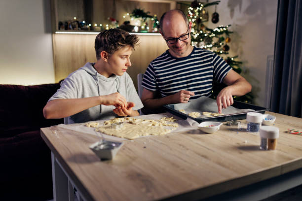 father and teenage son making cookies for christmas - pastry cutter family holiday child imagens e fotografias de stock