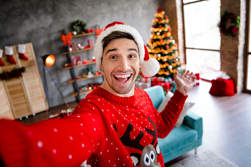 Photo of excited positive funky person make selfie arm demonstrate welcome newyear decorated house indoors.