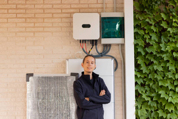 Front view of young man worker technician looking to camera with arms crossed with a solar system behind for alternative energy