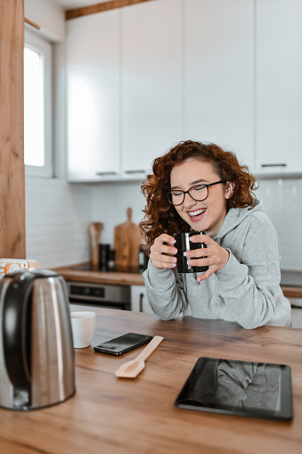 Smiling Female Drinking Coffee Before Starting To Cook In Kitchen