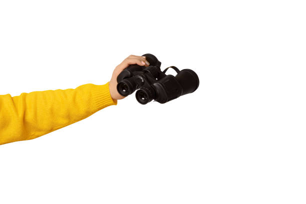 istock binoculars in hand isolated on white background, find and search concept. 1742660803
