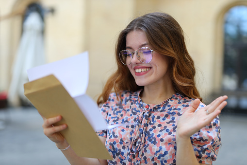 A young woman, happy and cheerful, reading a document for her education.