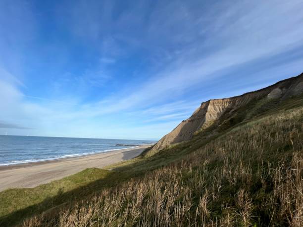The sea meets the sky as fluffy clouds paint a beautiful scene.