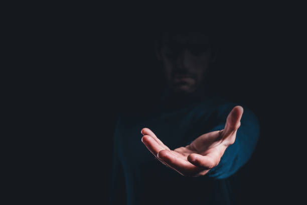 istock Male hand holding showing or giving something over black background, copy space for text. 1742670736