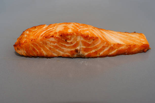 A freshly grilled skinless salmon fillet with a delightful texture and golden roasted tones,  arranged on a neutral gray background
