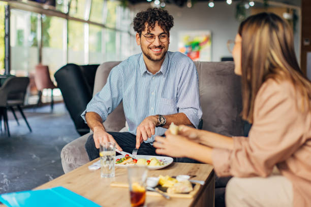 istock A man eats chicken in spinach sauce and a woman eats a wrap sandwich during a lunch break 1742677415