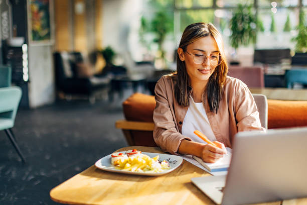 istock Before starting lunch, a woman uses a laptop and writes notes while sitting in a restaurant 1742679207