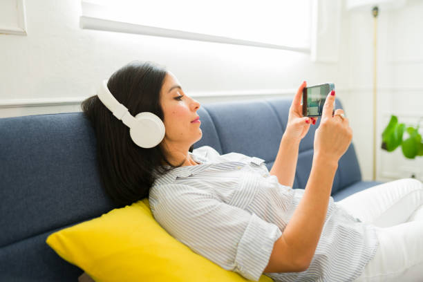 istock Relaxed young woman watching a streaming video on her phone using and app to learn and study English online at home 1742684609