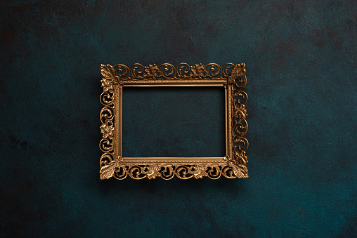 Beautiful antique wooden frame, painted in gold with flowers engraved in a series of black ovals and engraved angles. Empty, on white background.
