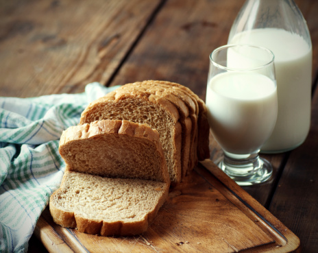 Whole grain bread with a glass of milk on wooden table