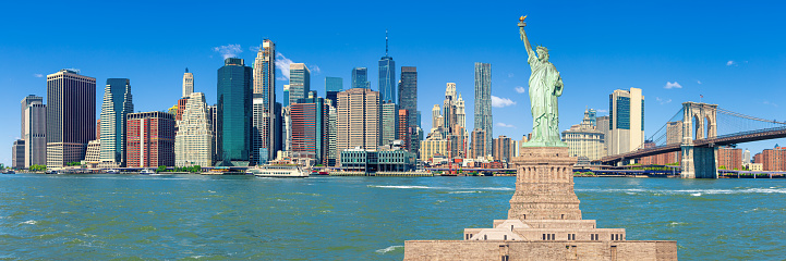 Stitched Panorama of Statue of Liberty and Manhattan Lower East Side Financial District, Brooklyn Bridge, World Trade Center, Blue Sky with Clouds and Water of East River, New York, USA. Canon EOS 6D (Full Frame censor) DSLR and Canon EF 24-105mm f/4L lens. 3:1 Image Aspect Ratio.