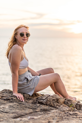 A striking stock image featuring a beautiful redhead in her 20s, set against the backdrop of a picturesque sunset by the water. The subject exudes a captivating charm while wearing stylish sunglasses, perfectly complementing the warm, golden hues of the evening.

In this photograph, the young woman's radiant beauty shines through as she takes in the serene atmosphere of the waterfront. Her sunglasses add a touch of contemporary flair to her look, and her natural grace harmonizes with the tranquil setting.

This image beautifully encapsulates the allure of youthful beauty and the serene ambiance of a waterfront sunset. It's an ideal asset for a wide range of creative projects that seek to capture the essence of a vibrant, redheaded woman at the magic hour by the water.