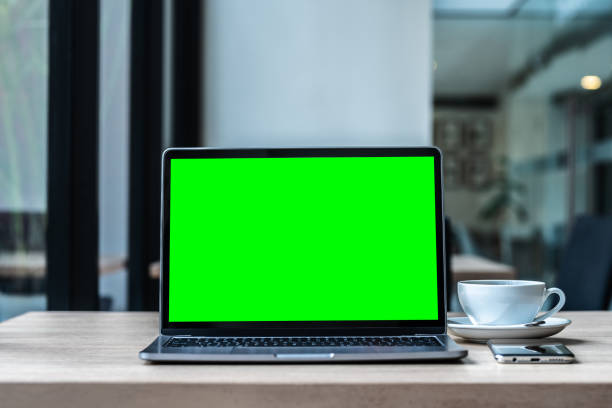 istock Mockup of laptop computer with empty screen with coffee cup and smartphone on table of the coffee shop background,Green screen 1742714477