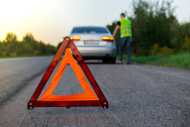 istock Unrecognizable sad driver in reflective vest. Male driver standing near broken car with open up hood. Red triangle to warn other road users of car breakdown or engine failure stop at countryside highway. Emergency traffic 1742718219