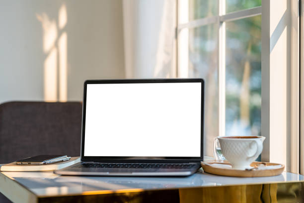 istock Mockup of laptop computer with empty screen with coffee cup and smartphone on table beside the window of the coffee shop background,White screen 1742721542