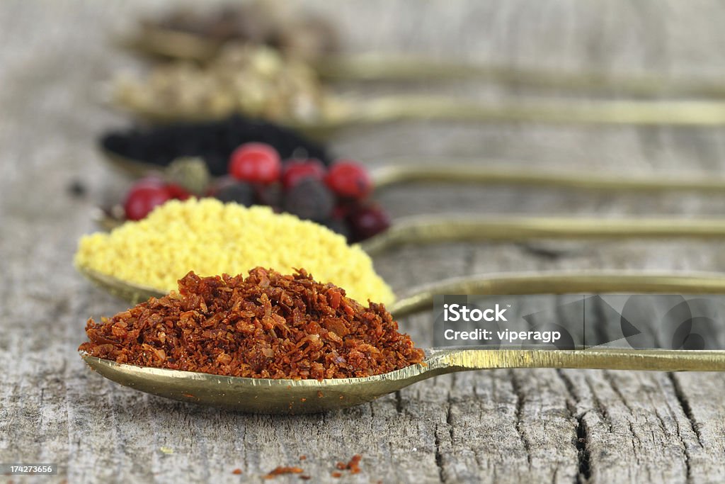 Old spoons with spices on wooden background Condiment Stock Photo