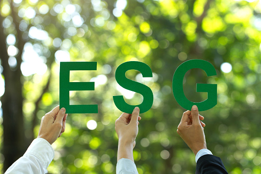 ESG concept of environmental, social, and governance.Hand of business people holding a paper with the word ESG to represent doing business that participates in solving environmental, social