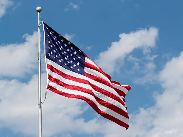 US Flag Waving in Blue Cloudy Sky stock photo