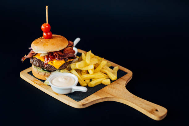 istock Delicious hamburger on a cutting board, decorated with cherry tomatoes and with two sauces on the side 1742747579