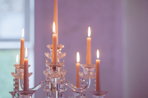 A transparent candelabra sparkling with eight elegant white candles decorates a luxurious wedding banquet hall, creating a romantic and sophisticated atmosphere of the celebration.