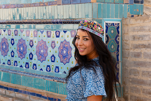 Lady wearing Uzbek traditional hat, Samarkand, Uzbekistan. in the background beautiful blue tiles