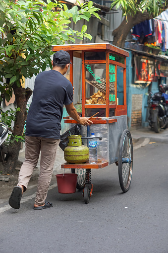 Jakarta, Indonesia - October 3, 2023: A man selling bakso cuanki on a cart. Indonesian street food. Small business entrepreneur.