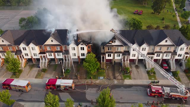 Stunning top view of house burning in flames and firefighters with fire trucks throwing tons of water. Toronto, Canada