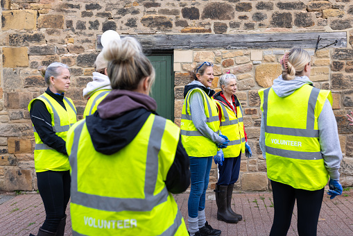 Three-quarter-length shot of a group of colleagues volunteering at a dog shelter located in Newcastle Upon Tyne. They are all wearing high-visibility jackets.