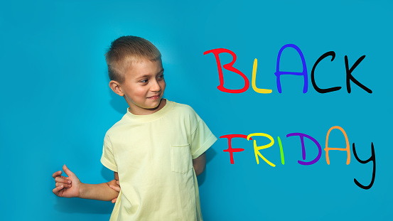 Banner with colorful sign about black friday. Portrait of a boy on a blue background looks away with a happy face. Front view