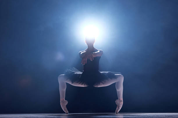 istock Attractive young woman, professional ballerina making performance, dancing on stage ever blue background with smoke effect 1742806498