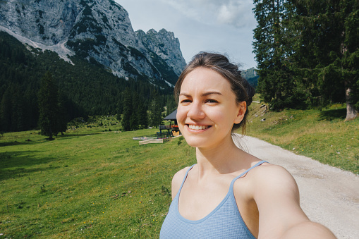 Smiling woman taking selfie portrait on a hike in Austria