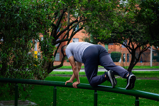 young sportsman in sportswear doing front squat on one leg forward with hands folded outside in city park during routine workout in morning