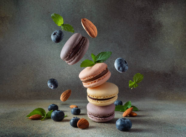 istock Colored macaroons with mint leaves, almonds and blueberries are falling down. Levitating colored macaroons with different flavors 1742808806