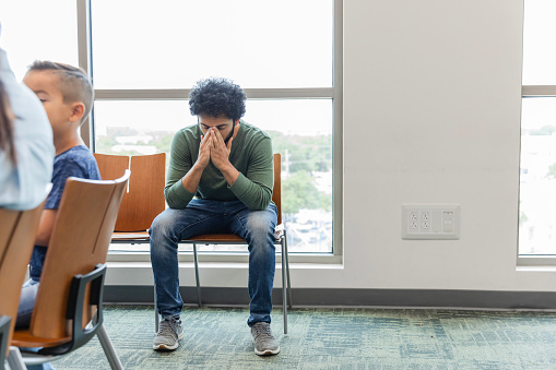 At the health fair, the emotionally distraught young adult man waits to see a mental health professional.