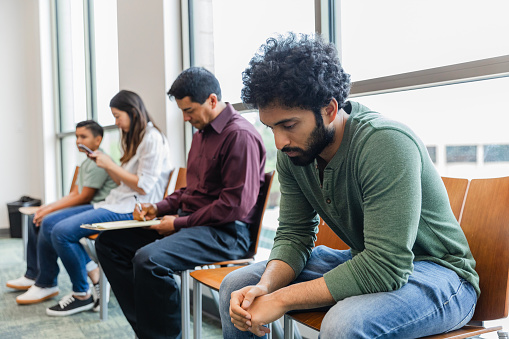 In waiting room, young adult man does serious thinking