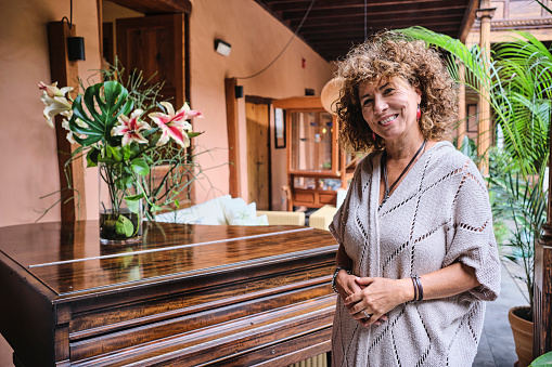Mujer posa sonriente frente a un piano en el interior del patio de un hotel
