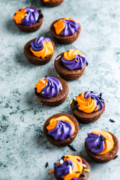 istock Brownie cupcakes with ghost cream decor and sprinkles on a slate board on a gray background. Happy Halloween concept. American culture and traditions 1742822054