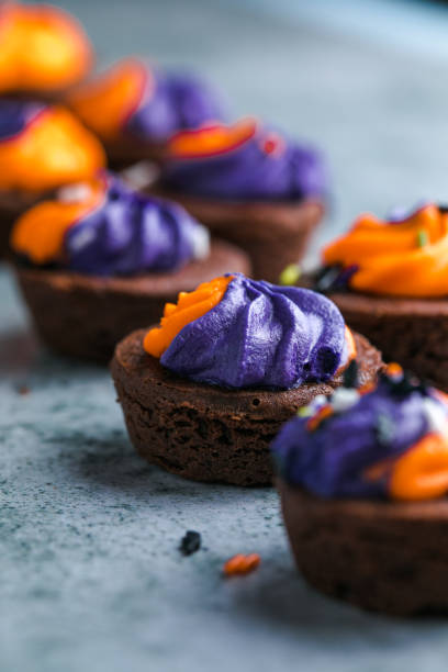istock Brownie cupcakes with ghost cream decor and sprinkles on a slate board on a gray background. Happy Halloween concept. American culture and traditions 1742822617
