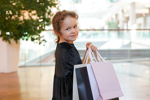 Child girl with shopping bags walking in shopping mall