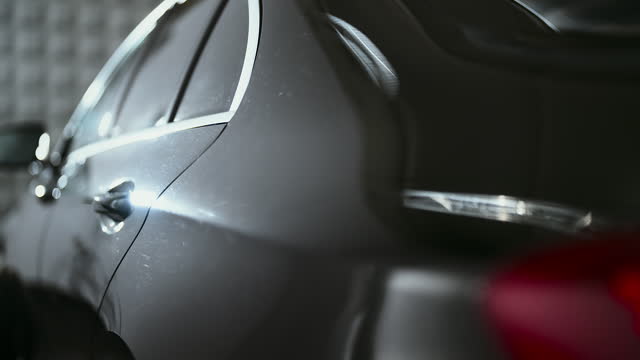 Close-up camera pan shiny reflective black surface of a brand new waxed car rear