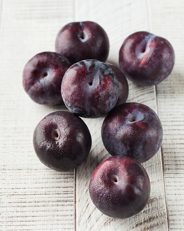 Ripe juicy plums on a white wooden background. The concept of fruit harvesting