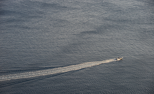 A speedboat going in the middle of the blue and tranquil sea.