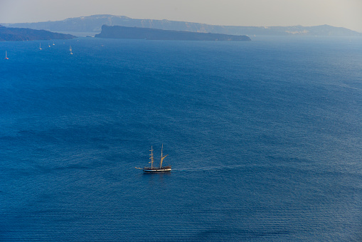 A sailing boat going in the middle of the blue and tranquil sea.