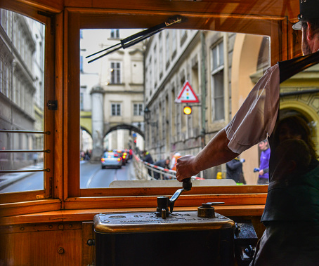 Prague, Czechia - Oct 26, 2018. The tram driver in cockpit of vintage wooden tram shown on a street while driving in Prague, Czechia.