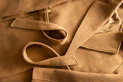 Top view of a beige cashmere coat. Warm background.