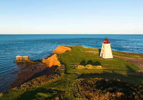 Aerial drone photograph of Cape Egmont Lighthouse on Prince Edward Island at golden hour sunrise